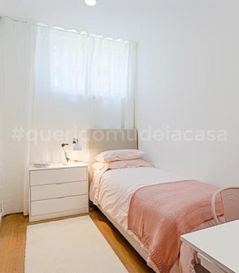 quarto de solteiro com cor principal rosa, mesa de cabeceira com três gavetas e um tapete branco comprido